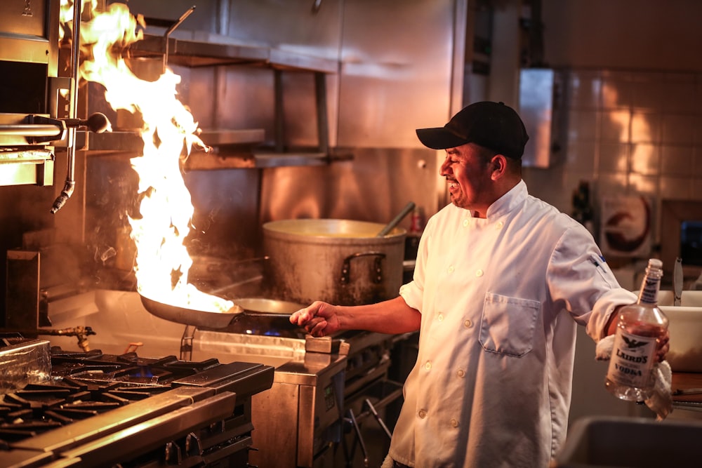 A line cook working a flaming pan on a restaurant line